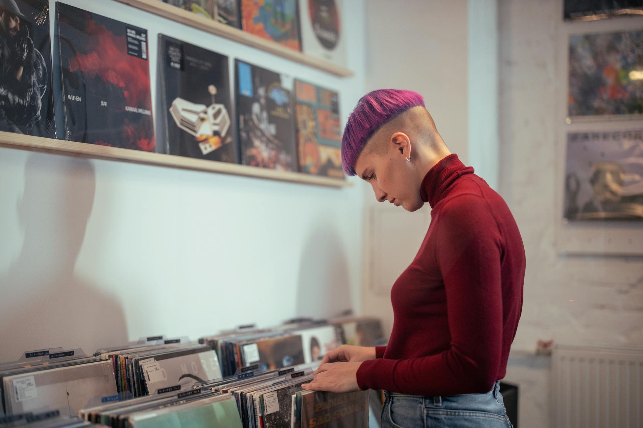Young woman with trendy hairstyle exploring a vinyl collection at a music store, vintage ambiance.
